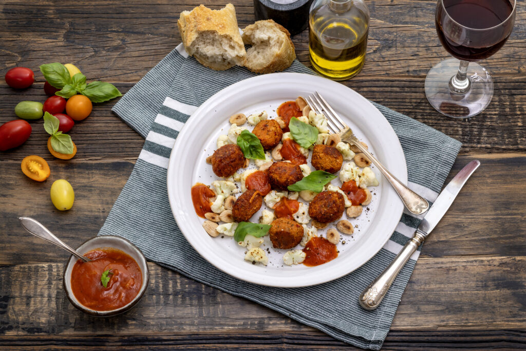 Ett dukat bord med en vit tallrik med italienska grönsaksbullar och tillbehör